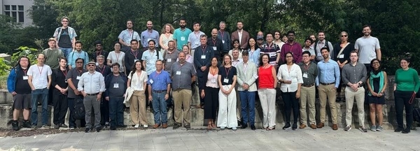 Three rows of people standing together facing forward and smiling.