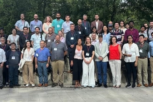 Three rows of people standing together facing forward and smiling.